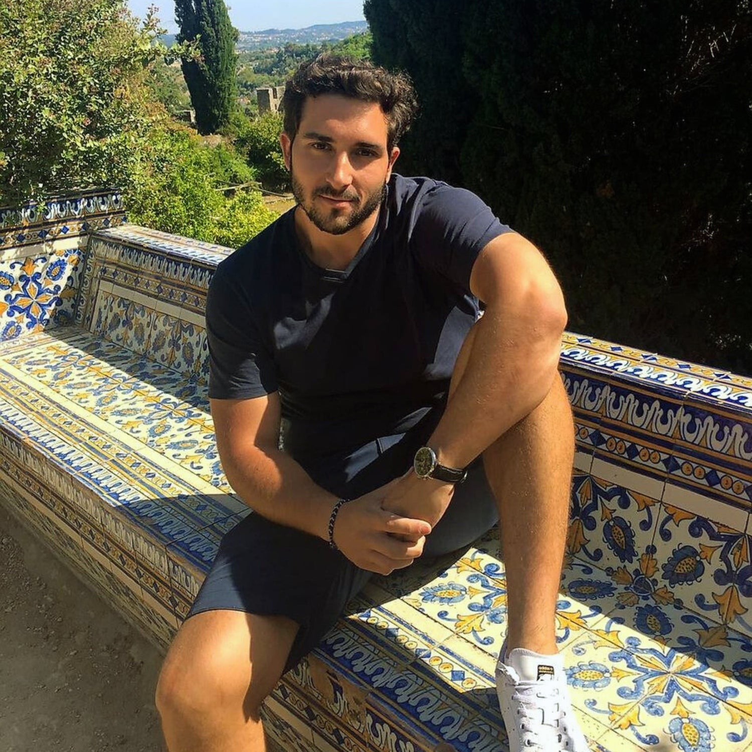 David, fondateur et CEO de FLAMARDA, assis sur un banc décoré aux motifs portugais, représentant la vision artisanale et haut de gamme de la marque de linge de bain.