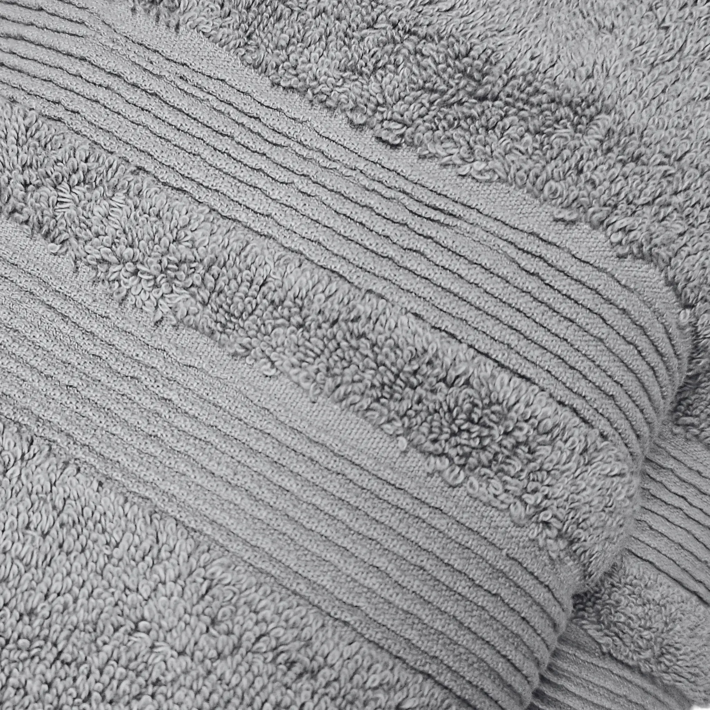 Gros plan sur la texture raffinée de la serviette de bain FLAMARDA gris de la collection Lagune, en coton de qualité supérieure pour un confort optimal. Idéal serviette cheveux visage/mains