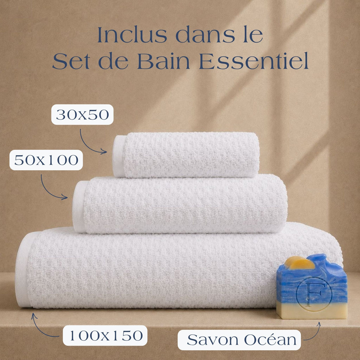 Set de Bain Essentiel FLAMARDA Prestige Dune Blanc Nacre comprenant un drap de bain 100x150cm, une serviette 50x100cm, une serviette invité 30x50cm et un savon artisanal Océan, présentés dans une ambiance inspirée des plus beaux hôtels.