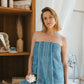 Femme dans une salle de bain élégante portant un drap de bain bleu horizon FLAMARDA, en éponge épaisse et moelleuse. Drap de bain haut de gamme inspiré de l’océan, alliant douceur et raffinement.