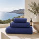 Serviettes de bain Prestige Dune Bleu Profond en coton peigné dans une salle de bain haut de gamme avec vue sur l'océan