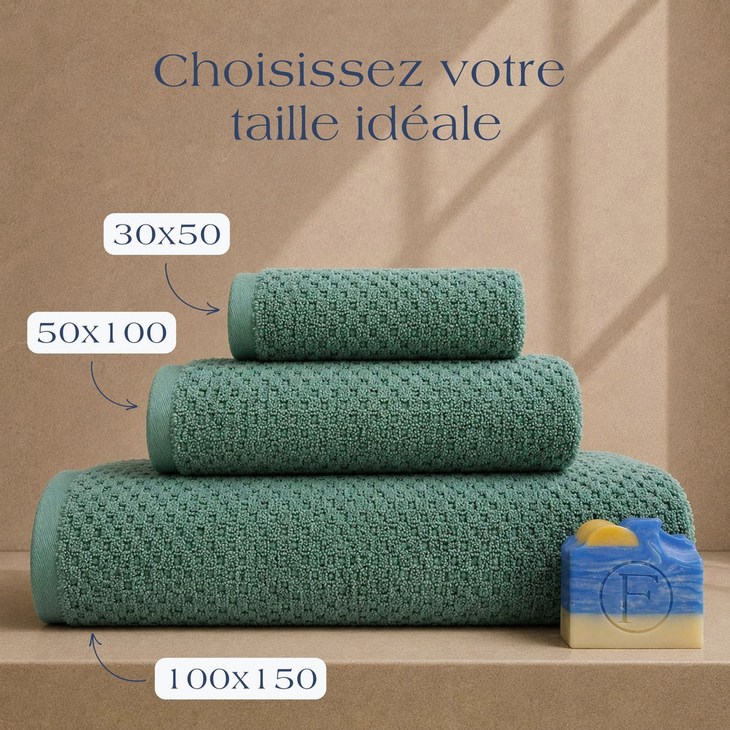 Guide des tailles FLAMARDA Prestige Dune Vert Azur présentant les dimensions 30x50cm, 50x100cm et 100x150cm. Serviettes de bain haut de gamme en coton peigné 600 g/m² dans une teinte vert azur apaisante.