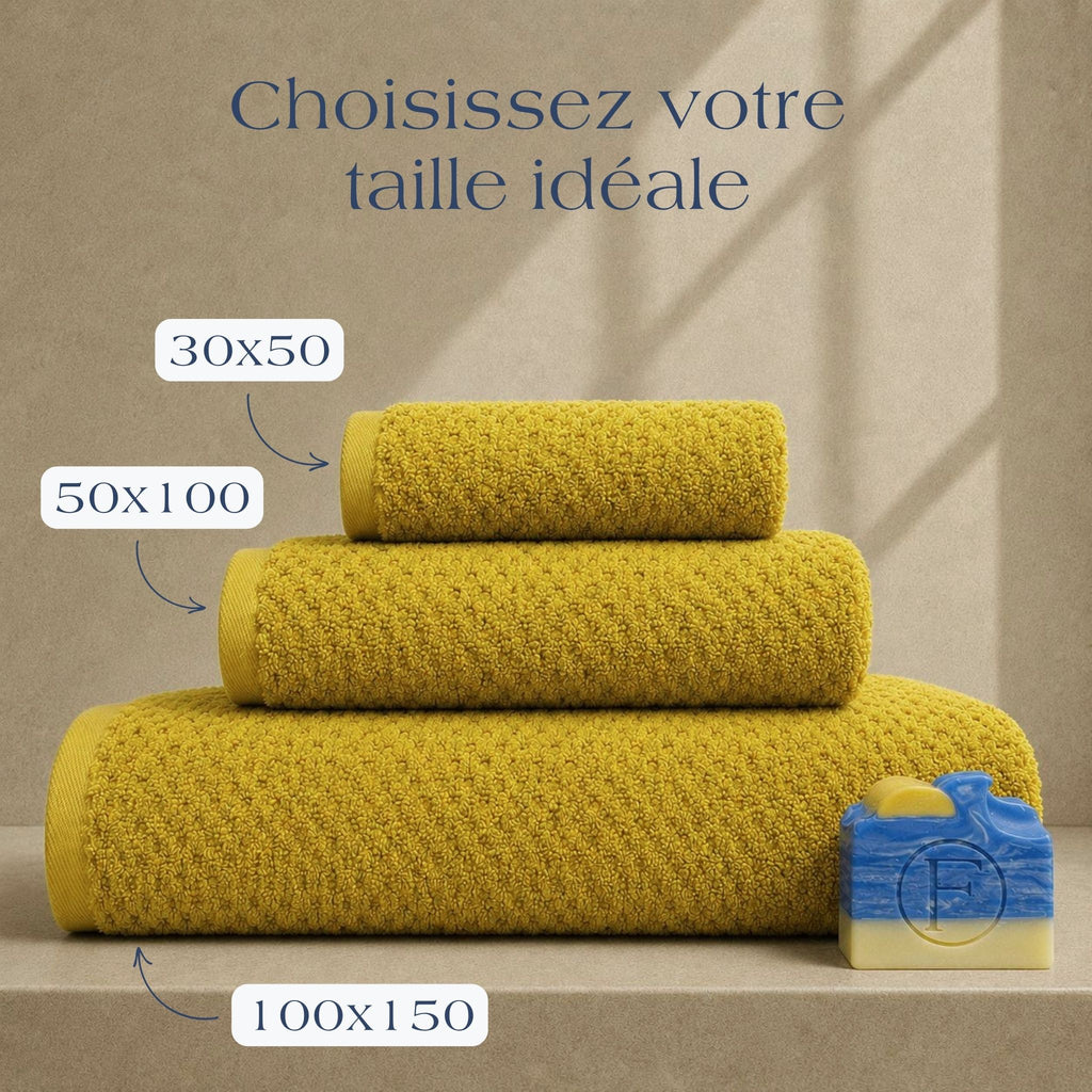 Guide des tailles FLAMARDA Prestige Dune Ocre Doré présentant les dimensions 30x50cm, 50x100cm et 100x150cm. Serviettes de bain haut de gamme en coton peigné 600 g/m² dans une teinte ocre doré lumineuse.