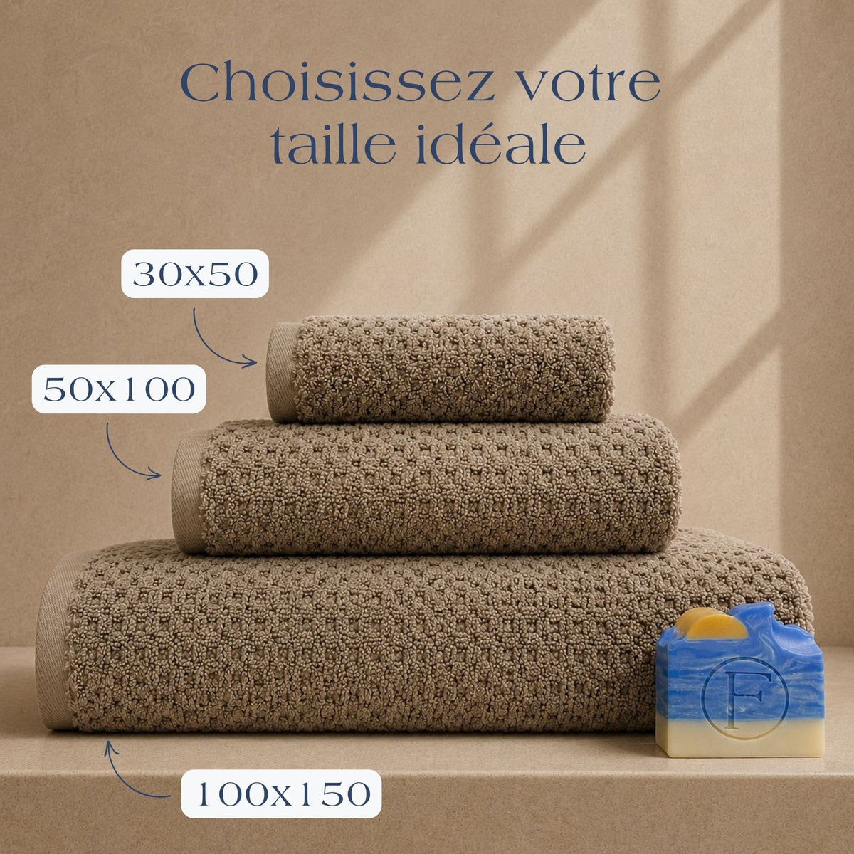 Guide des tailles FLAMARDA Prestige Dune Sable Brun présentant les dimensions 30x50cm, 50x100cm et 100x150cm. Serviettes de bain haut de gamme en coton peigné 600 g/m² dans une teinte sable brun naturelle et chaleureuse.