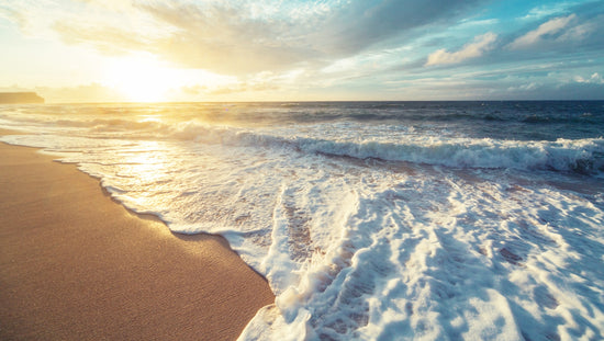 Plage ensoleillée avec vagues douces évoquant l’inspiration marine des serviettes de bain haut de gamme FLAMARDA