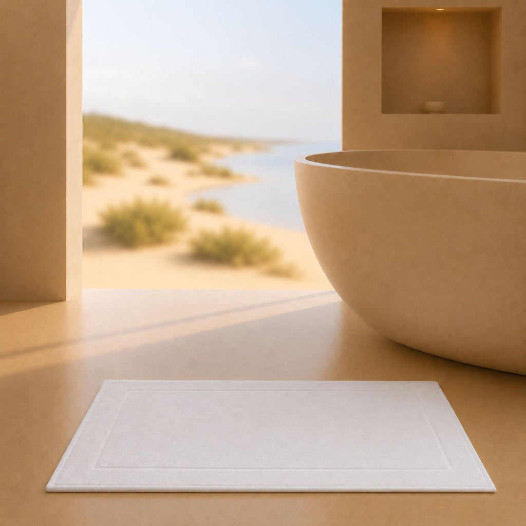 Tapis de Bain Sérénité Lagune Blanc Perlé 50x80cm dans une salle de bain élégante avec vue sur l’océan et les dunes du Portugal